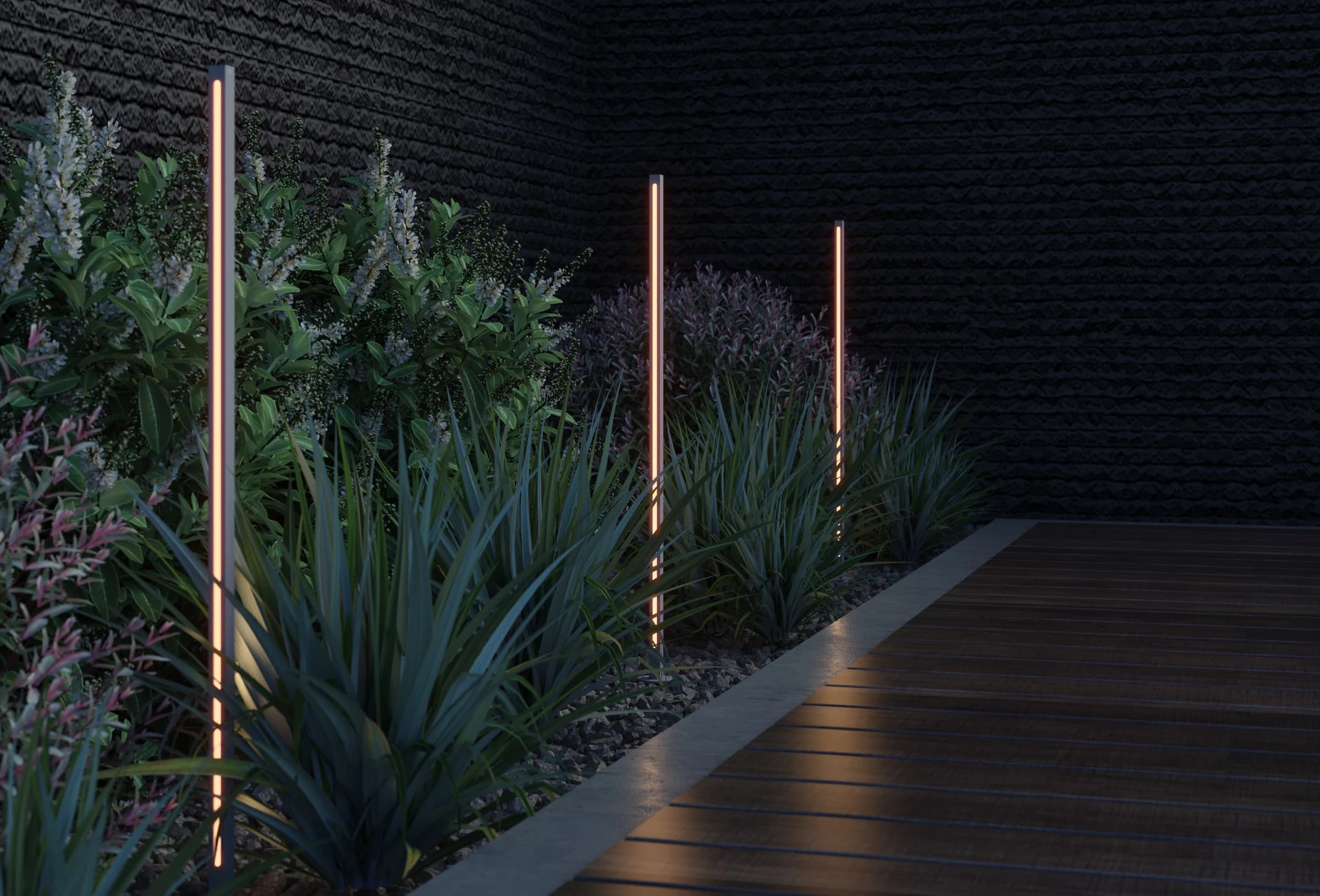 Garden pathway at night with outdoor pole lights illuminating tropical plantings